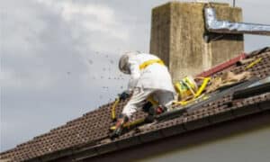 disinfestatore su un tetto intento a spruzzare insetticida per eliminare un nido di calabroni